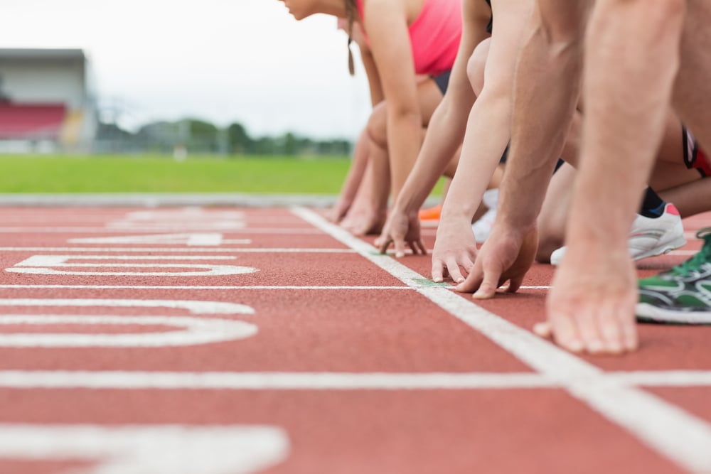 Close-up side view of cropped people ready to race on track field